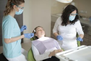 Dental professionals performing a check-up in a clinic setting with patient.